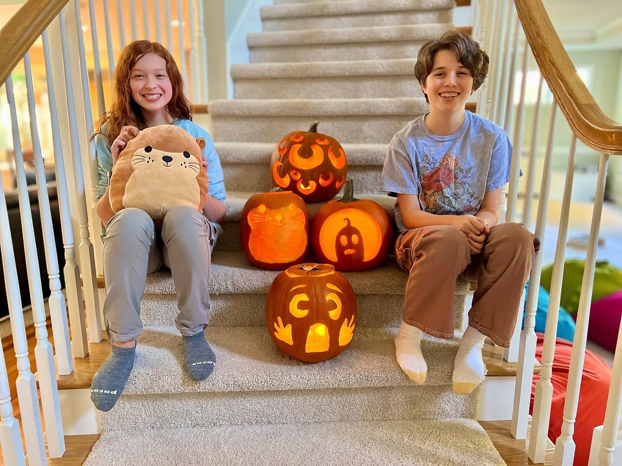 Jack O’Lanterns Children smiling beside lit jack-o-lanterns on a staircase.