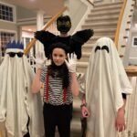 A family posing in creative Halloween costumes before a staircase.