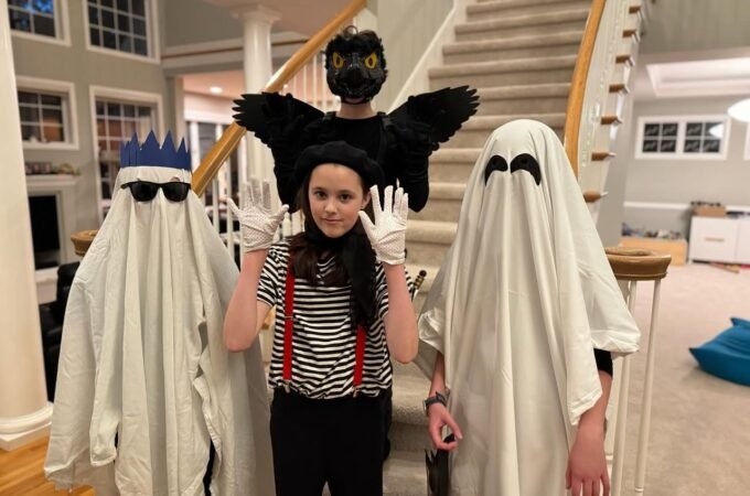 A family posing in creative Halloween costumes before a staircase.