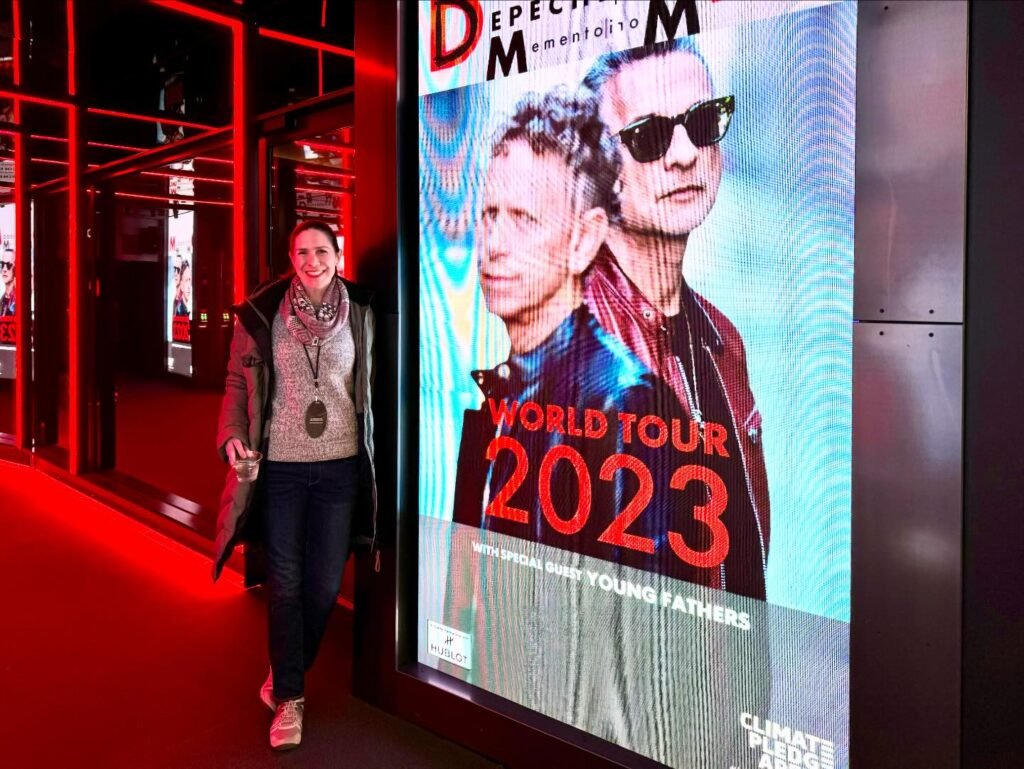 A person visits the Expo 2023 venue, shown alongside a close-up of a Depeche Mode 2023 World Tour poster.