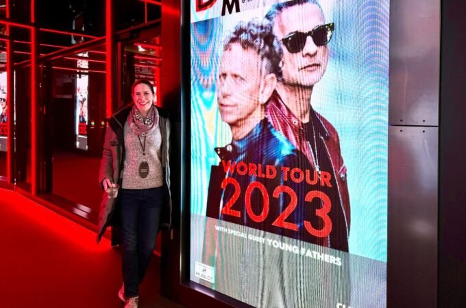 A person visits the Expo 2023 venue, shown alongside a close-up of a Depeche Mode 2023 World Tour poster.
