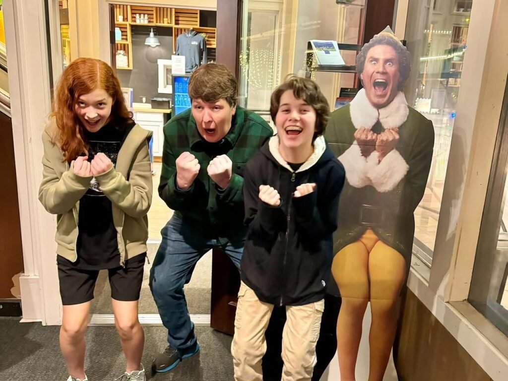 Three people mimic a mannequin's pose with excited expressions.