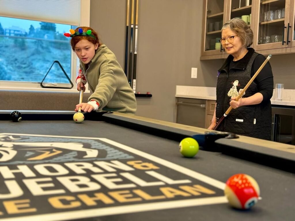 A person plays pool using a pool cue ball inside a dining area, with branded flooring text CHORNBELL CHELAN visible.