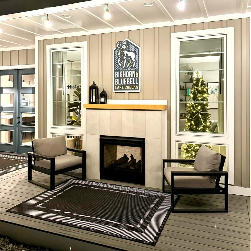 Comfortable seating area with armchairs and a rug in front of a stone fireplace and windows at Bighorn Bluebell Lake Chalets.