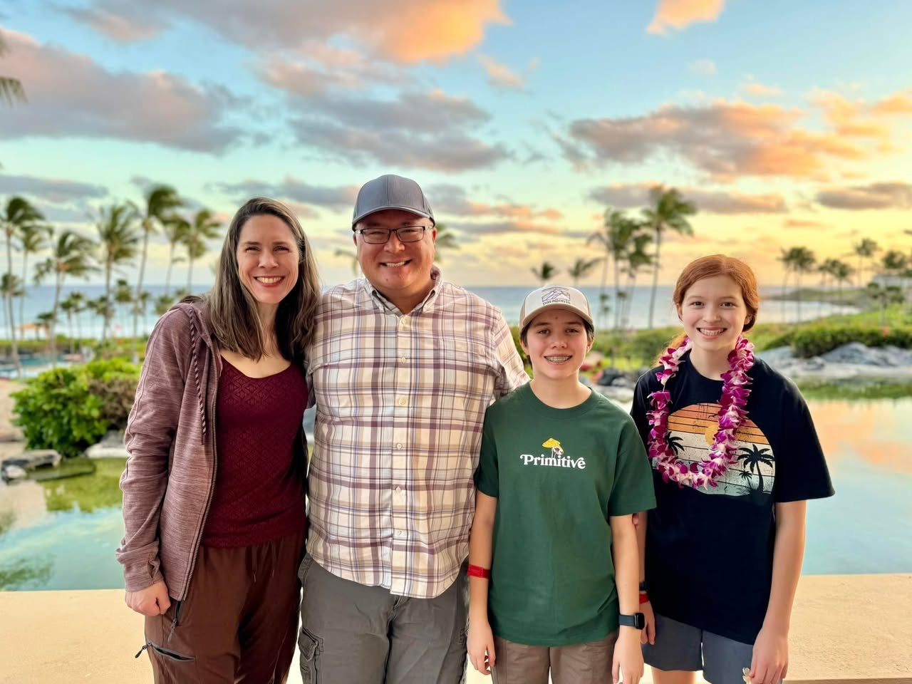 Sunset Dinner A family poses together at a tropical resort with palm trees and a pool in the background. The scene captures a beautiful sunset sky.