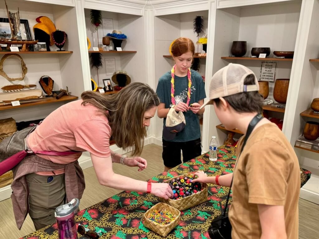 Visitors browse beads and cultural artifacts at an interactive museum display.