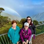 Kukui Nut Leis A family enjoys a scenic view of a rainbow over misty mountains from a lookout point in Monteverde Cloud Forest.