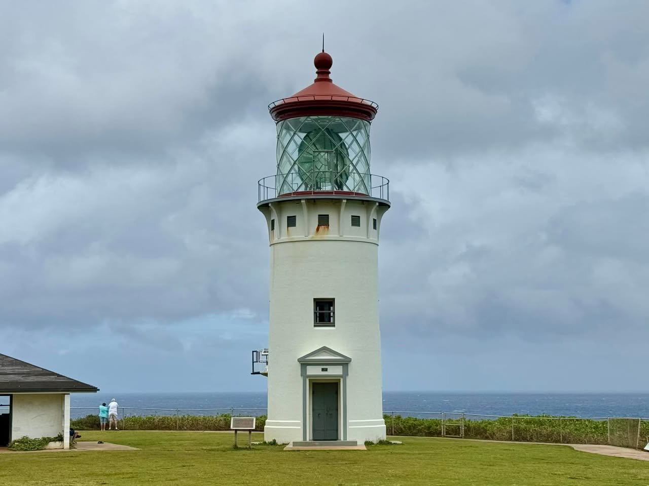 Kileaua Point National Wildife Refuge Lighthouse A white lighthouse with a red roof standing near the sea under a cloudy sky. Close up details of the lighthouse lens and a patio area.