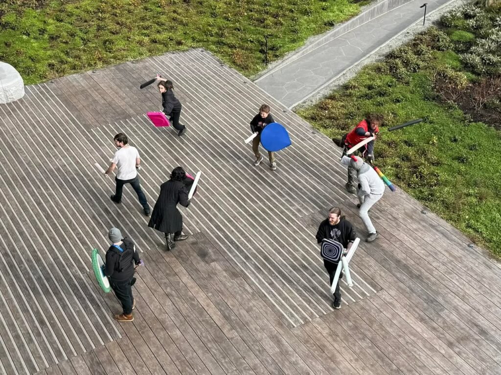 An overhead view of a group of people canvassing on an outdoor wooden platform surrounded by greenery.