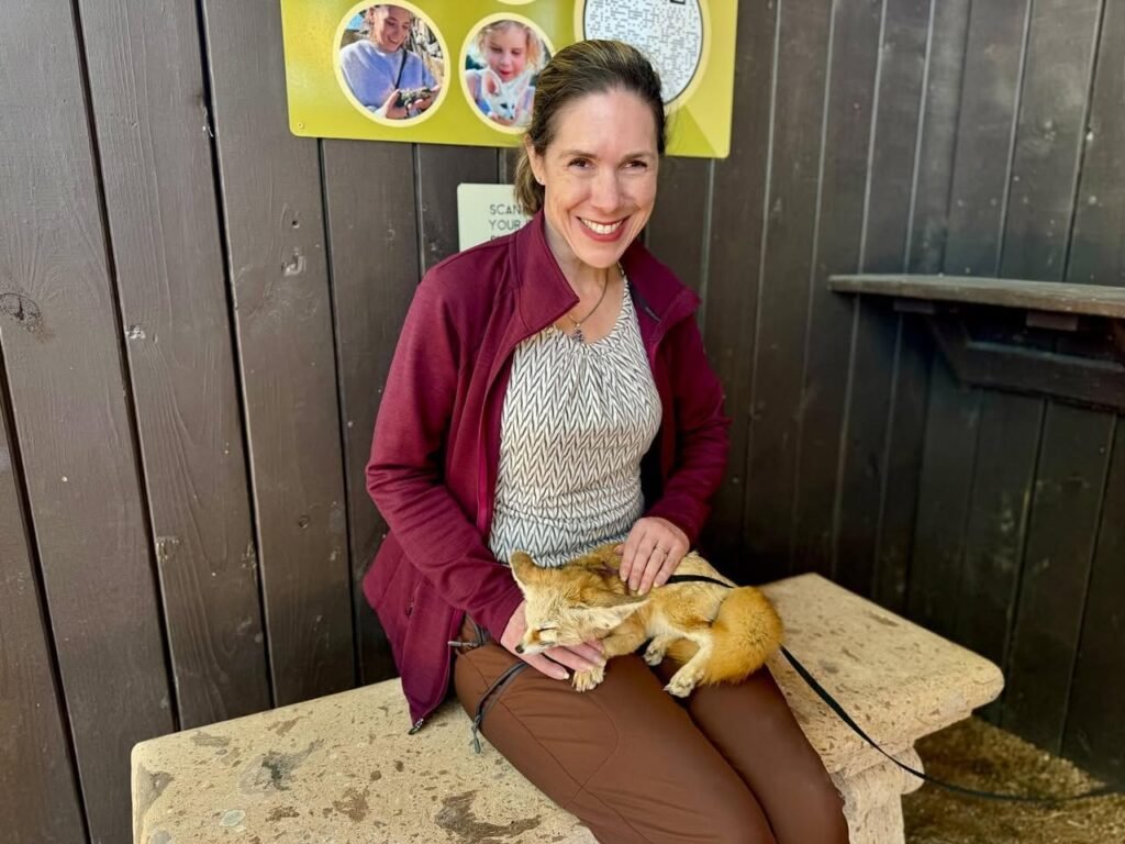 A smiling visitor cuddles a sweet orange cat on a bench during a trip to the Oregon Coast.