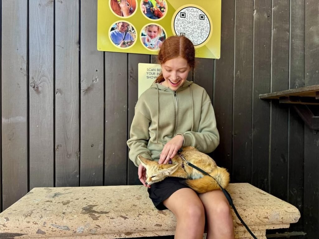 A child smiling softly while caring for a bearded dragon at a nature center playground.