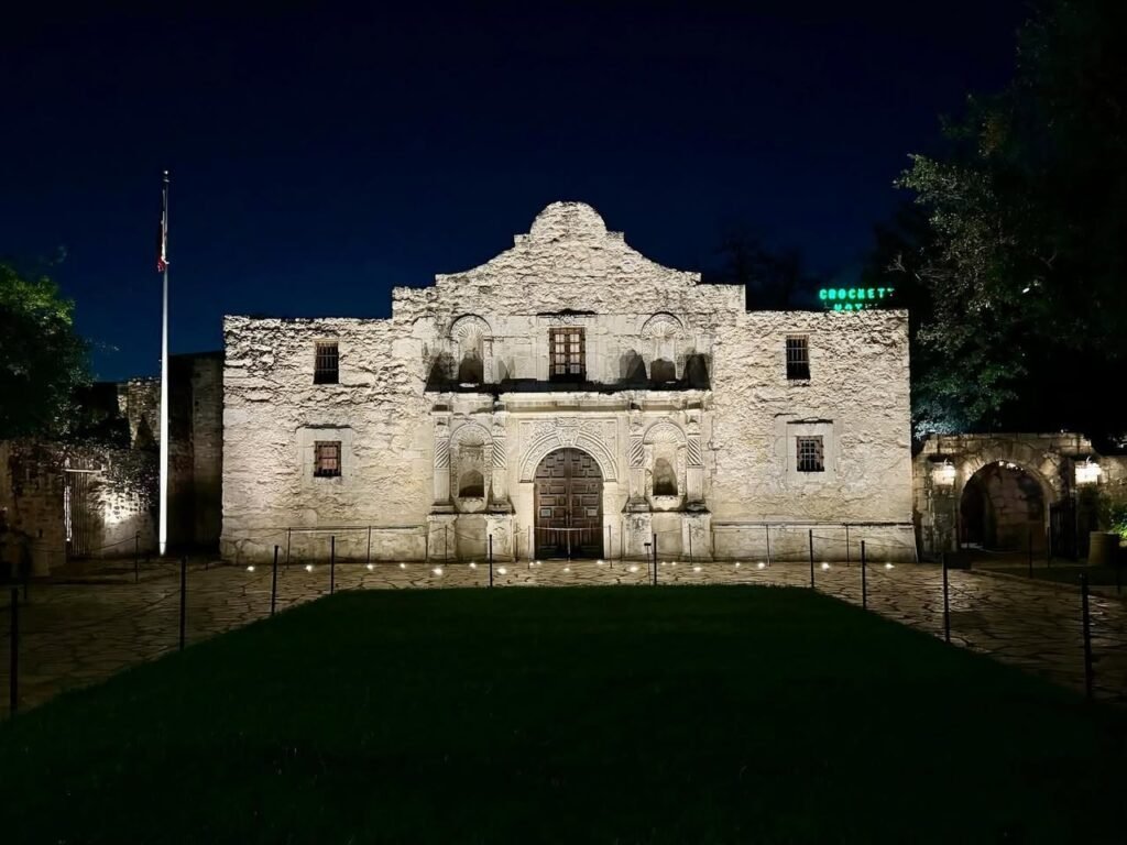 The Alamo's iconic facade brilliantly lit against a dark sky, showcasing its historical architecture.