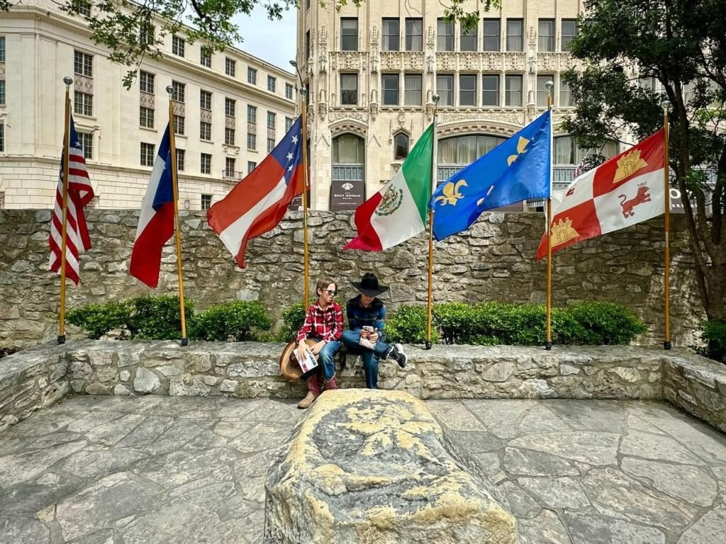 Tourists posing in front of the Pennsylvania state building with state and national flags.