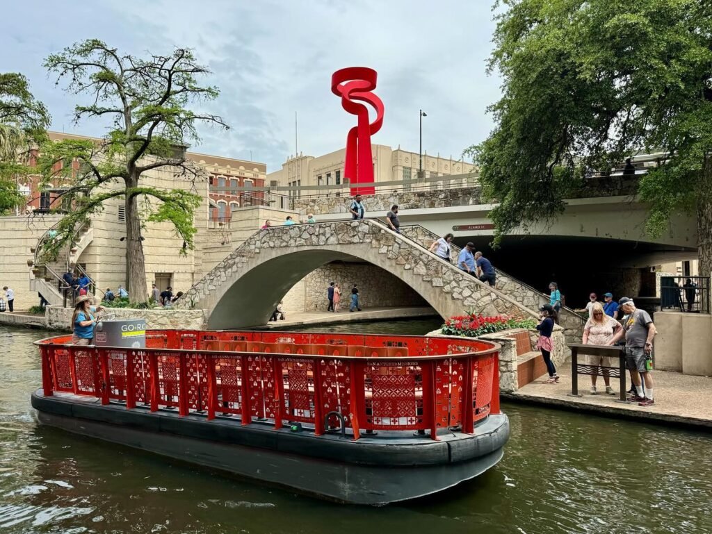 A vibrant red art sculpture adorns a bridge over the Seine, next to a unique red boat.