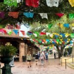 Lavaca, San Antonio Vibrant banners and flags stretch across a brick walkway and frame a large garden urn.