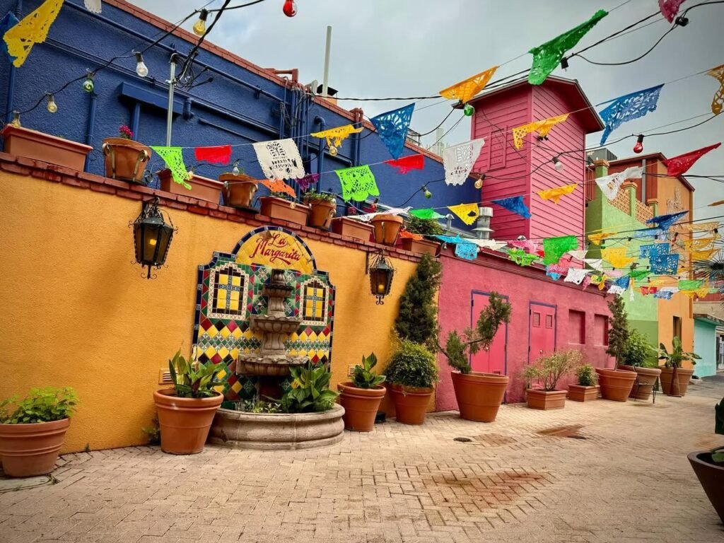 Colorful alleyway at San Diego's Tacos del Mar with vibrant Papeles de Colores decorations adorning blue and yellow walls.