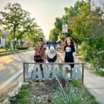 Two travelers standing beside the historic Lavaaca landmark sign on a cozy street in Galveston, Texas.