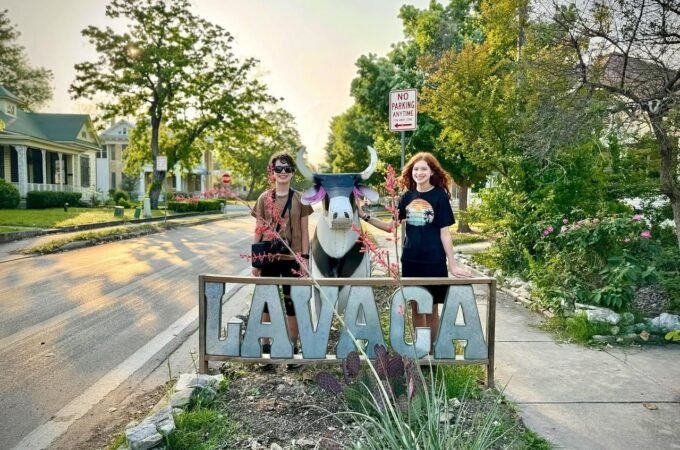 Two travelers standing beside the historic Lavaaca landmark sign on a cozy street in Galveston, Texas.