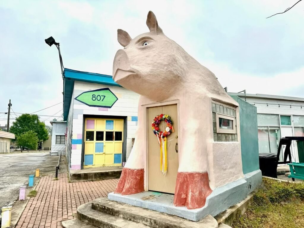 A building designed to resemble a large animal with a house number 507 and a wreath on the door. The structure features colorful tiles and stands out in an outdoor setting.