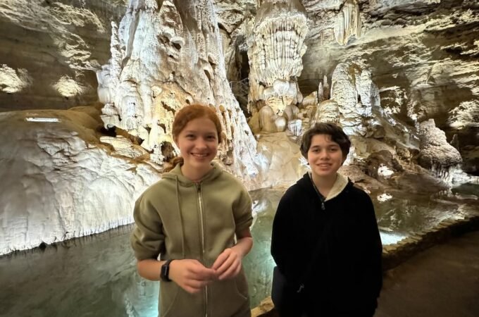 Visitors posing in a cave passage with limestone formations.