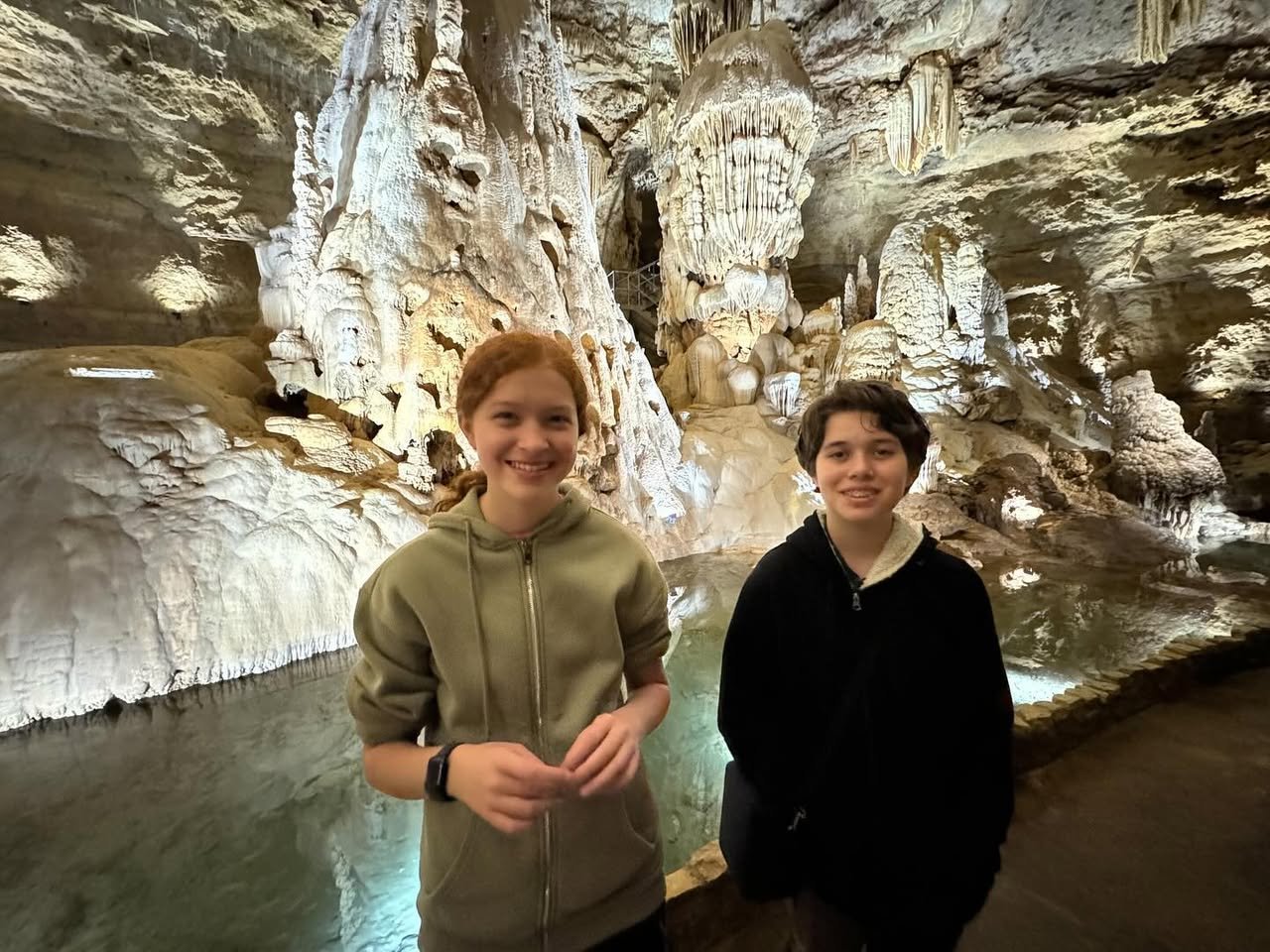 Natural Bridge Caverns Visitors posing in a cave passage with limestone formations.