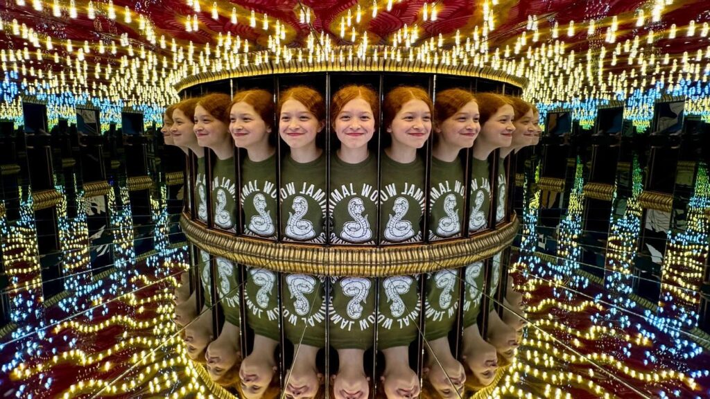 A person in matching replica green sweaters with a rabbit design appears multiple times in a distorted mirror maze setting.