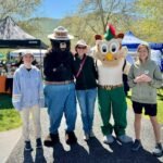 A group of people poses with two costumed mascots at an outdoor event.