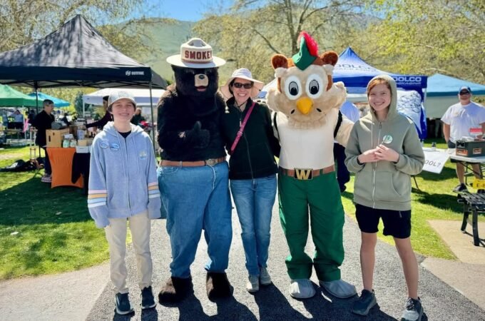A group of people poses with two costumed mascots at an outdoor event.