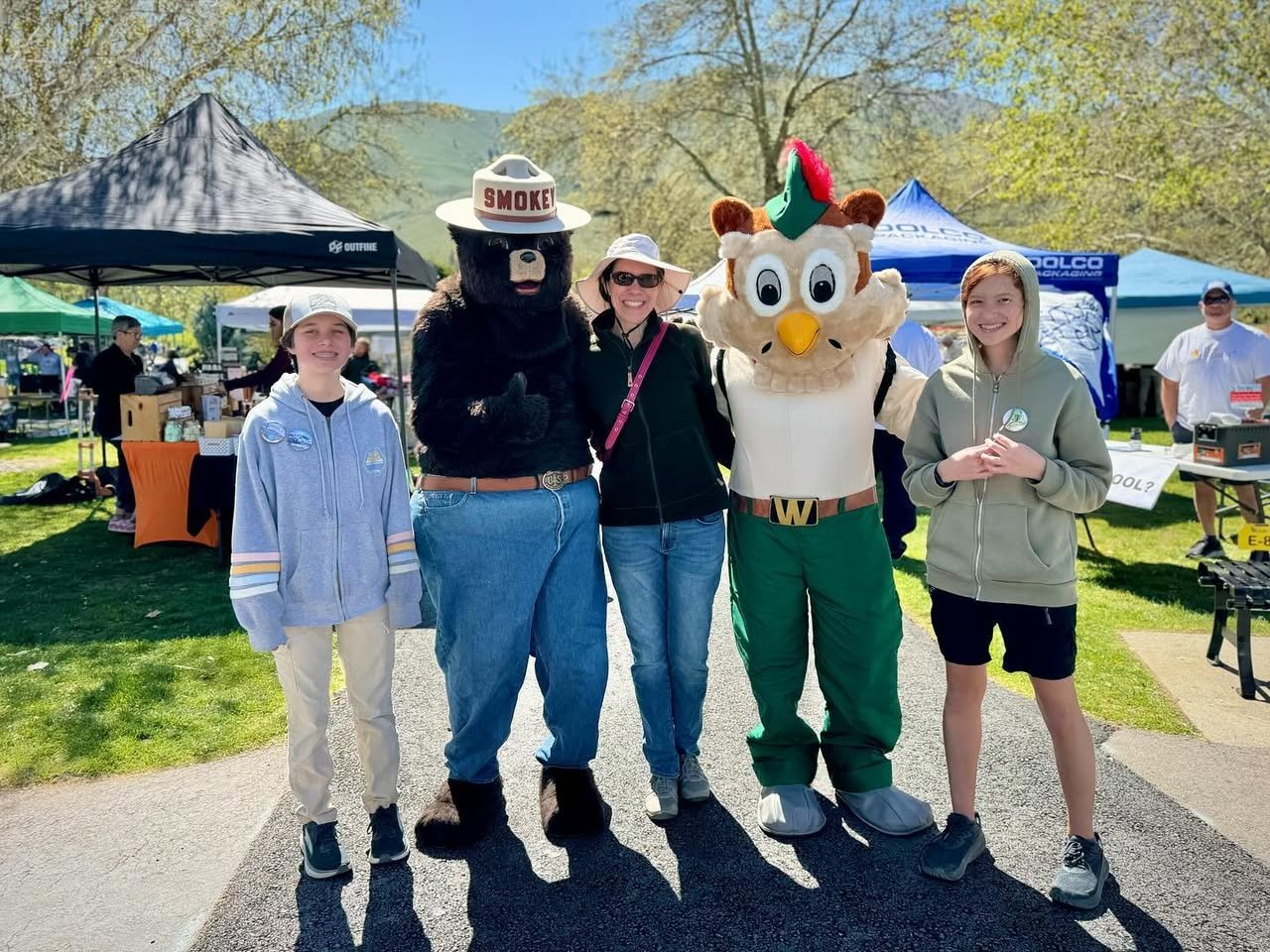 Earth Day in Chelan A group of people poses with two costumed mascots at an outdoor event.