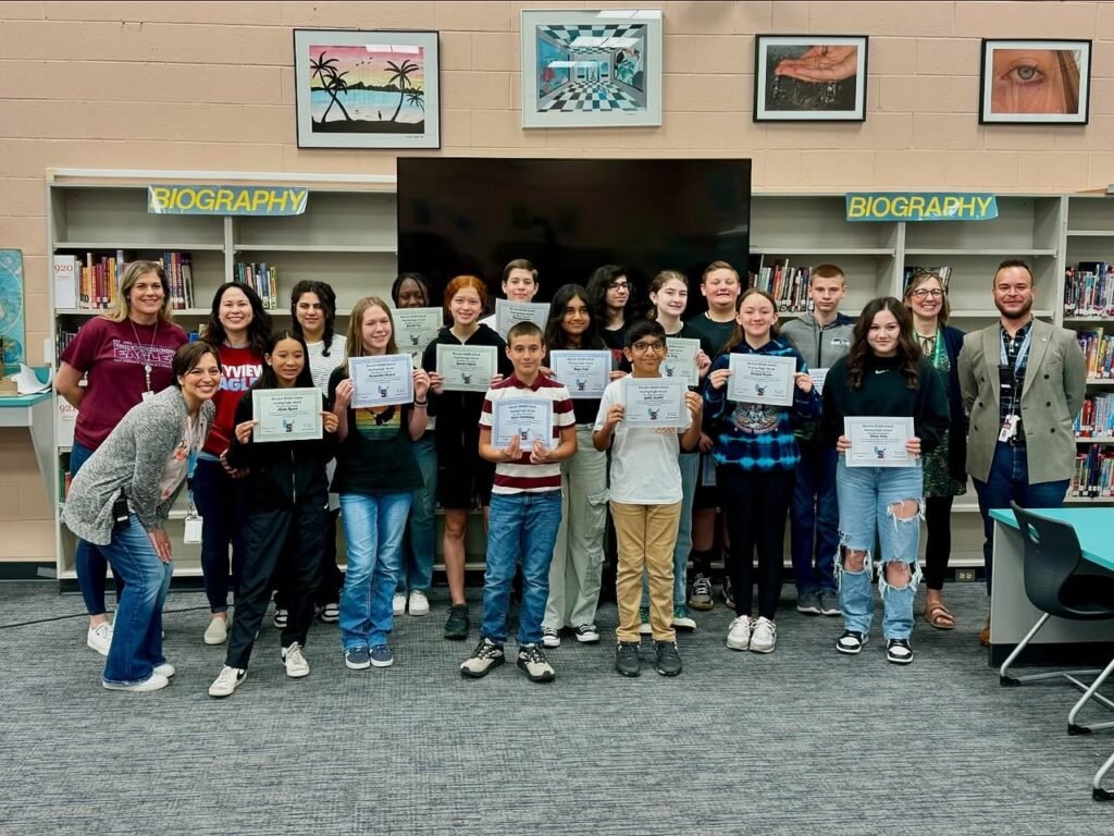 A group of people holding certificates in a library.