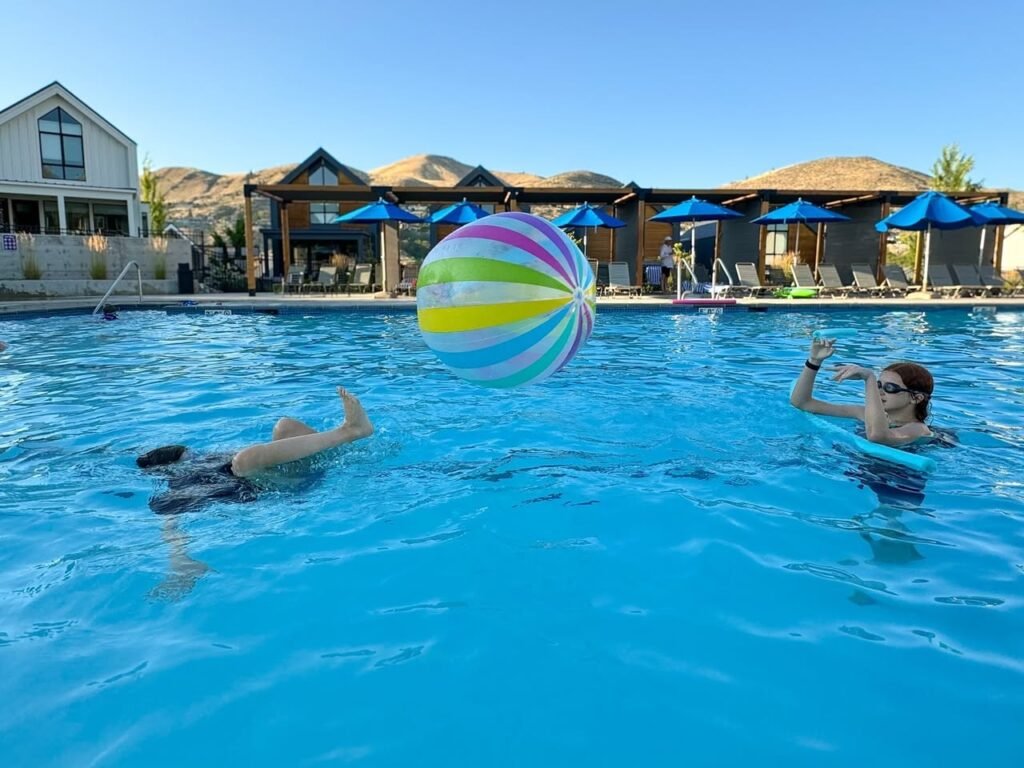 People enjoying a day at a resort pool with a colorful beach ball. They are swimming and tossing the ball around for fun.