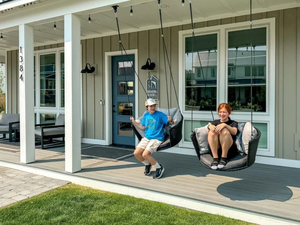 Two individuals relaxing in outdoor chairs on a home's front porch.