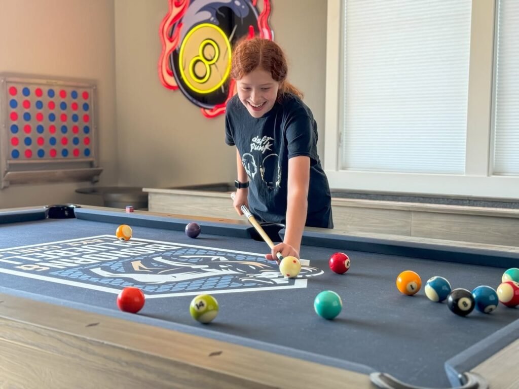 A young person playing pool on a blue table.