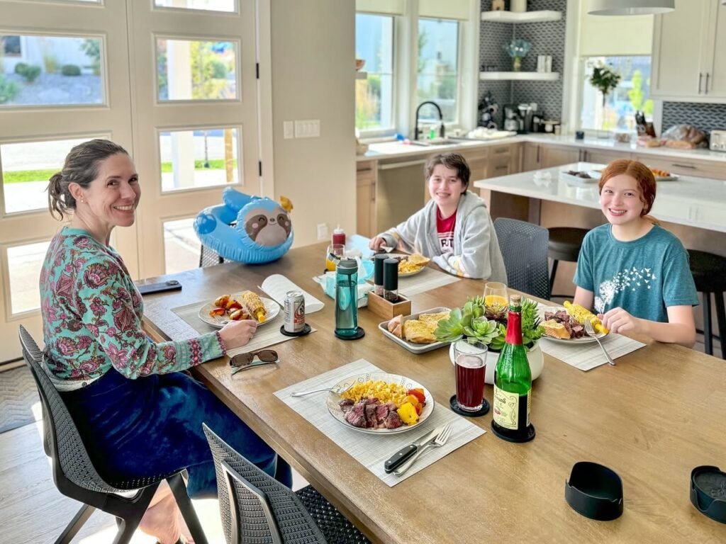 A family enjoying a meal together at a dining table in a modern kitchen with natural light.