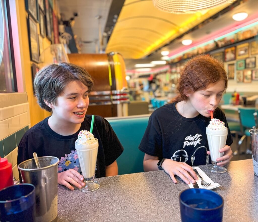 Two people enjoying milkshakes at a retro-style diner.