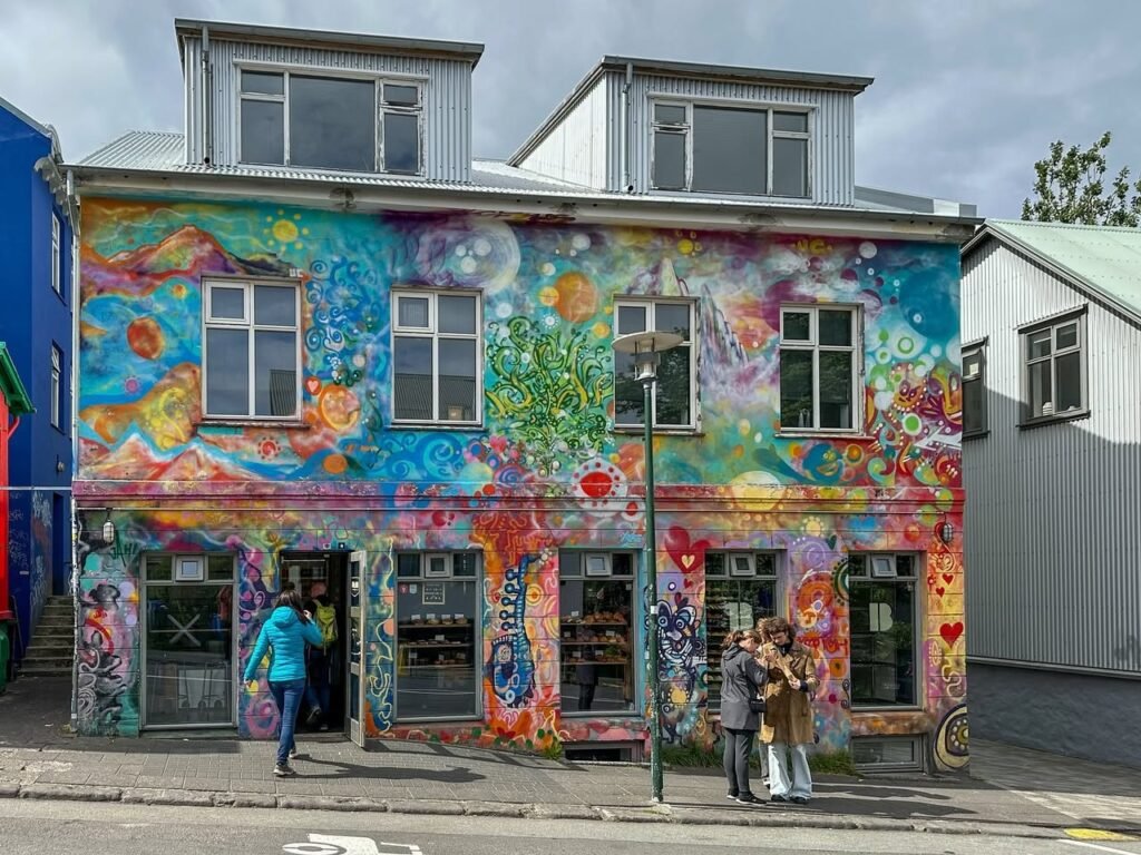 Two photos of a colorful mural covering the exterior of a building in an urban setting.