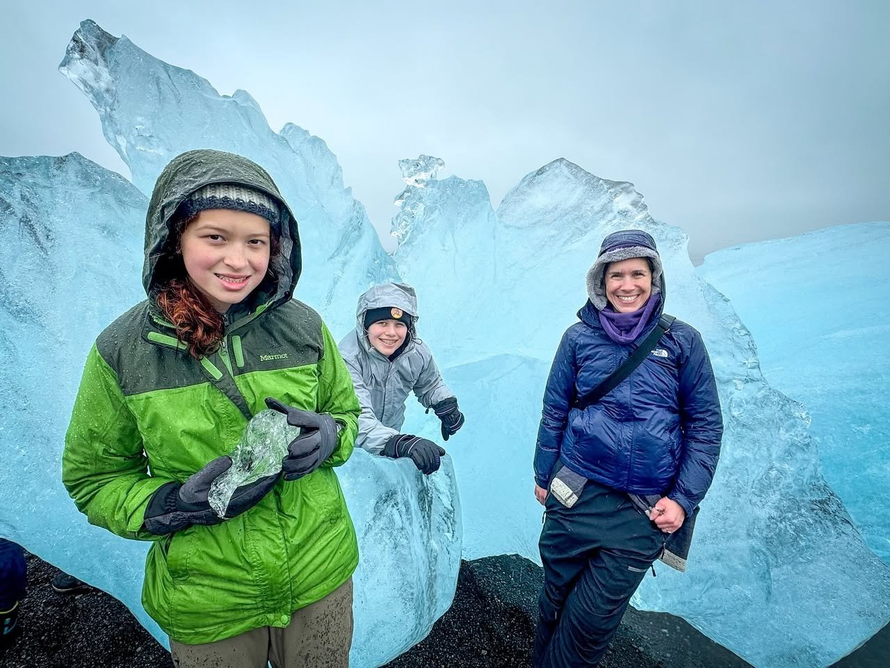 A family taking pictures on a glacier with stunning ice formations in the background.