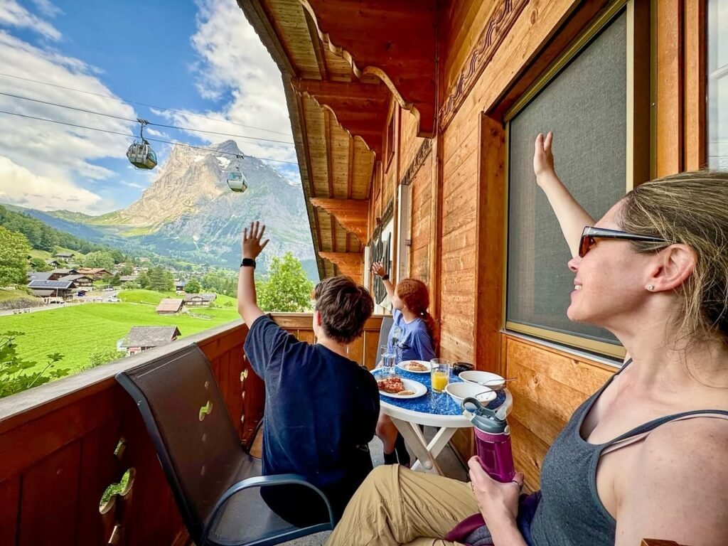 Travelers wave to cable cars from a wooden balcony with stunning mountain views in Costa Rica.