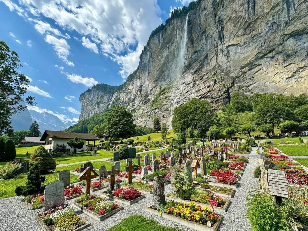 A beautiful garden cemetery at Viglefsfjella Church with vibrant flowers. towering Vettisfallene waterfall cascades down the cliffside.