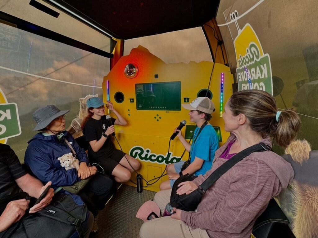 Passengers inside a parachuting aircraft enjoy karaoke on the lift. The interior scene includes the yellow karaoke box and crew.