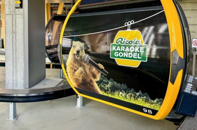 A yellow and black gondola car featuring a graphic of the Ricola Karaoke Gondol and a singing marmot.
