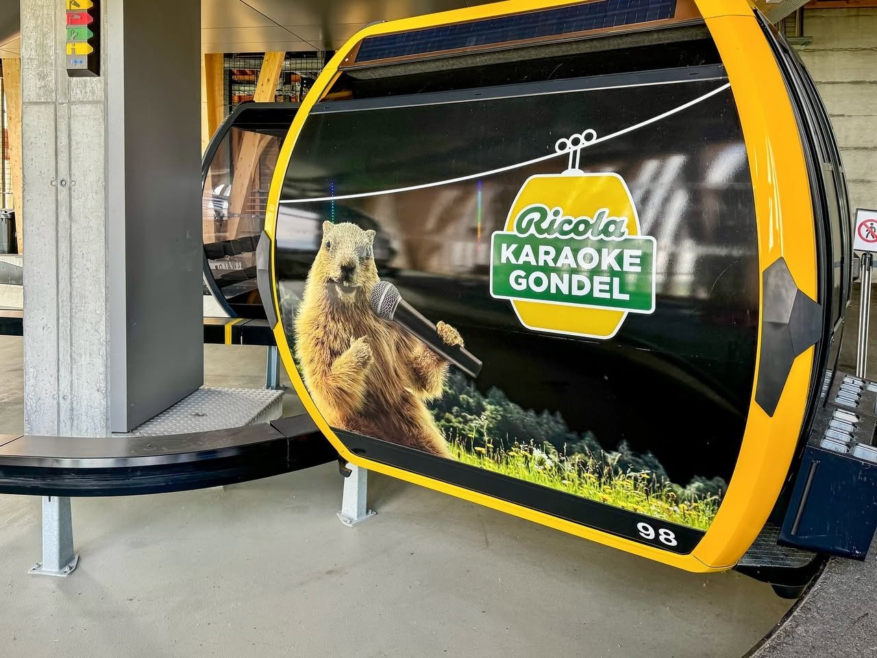 Karaoke Gondola A yellow and black gondola car featuring a graphic of the Ricola Karaoke Gondol and a singing marmot.