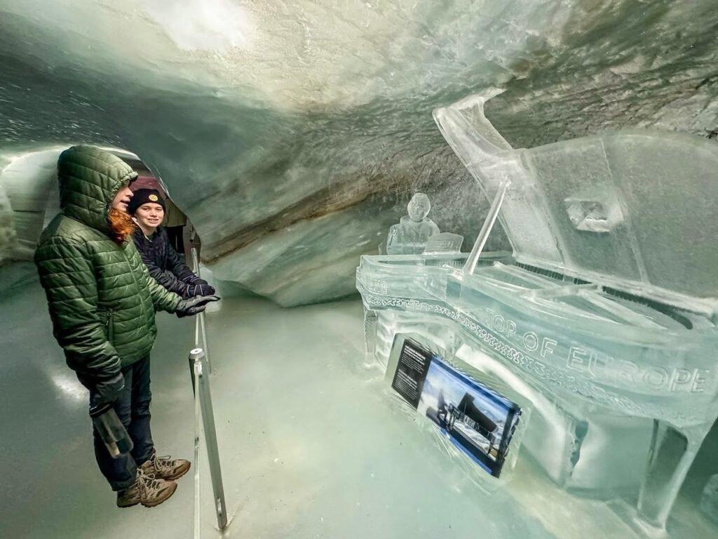 Visitors explore ice formations inside an iceberg, capturing its natural blue hues and crystalline structures.