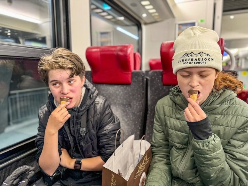 Two travelers enjoy a snack on a train.