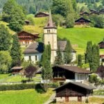 A picturesque Swiss alpine village with traditional wooden houses and a white church tower.