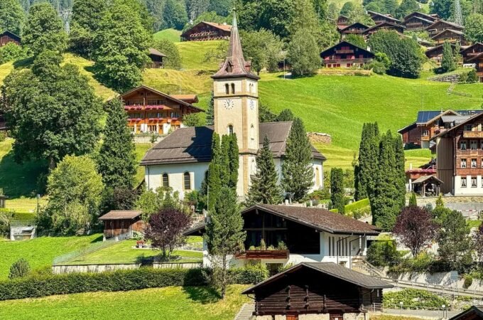 A picturesque Swiss alpine village with traditional wooden houses and a white church tower.
