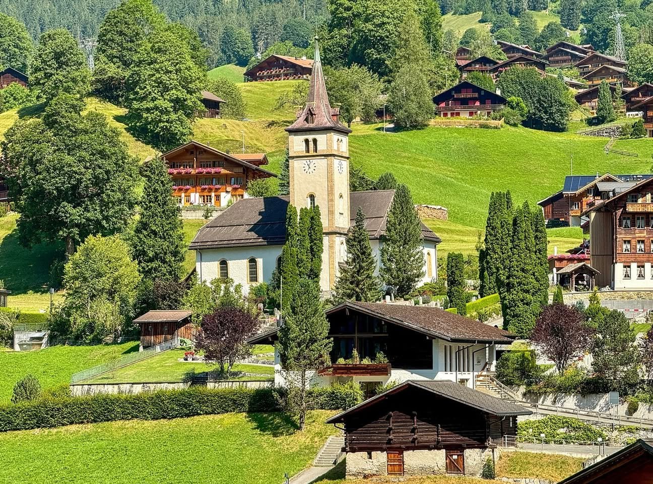 A picturesque Swiss alpine village with traditional wooden houses and a white church tower.