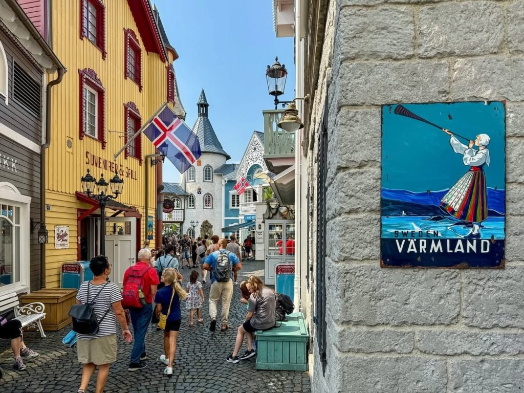 A vibrant cobblestone street in Sweden features a colorful yellow building with red trim and a Värmland plaque on a white stone wall.