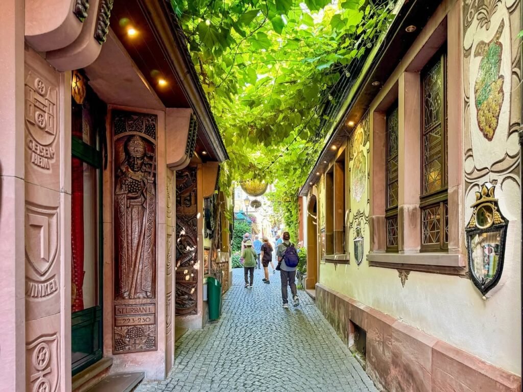A beautifully decorated passageway with intricate carvings and lush greenery overhead.