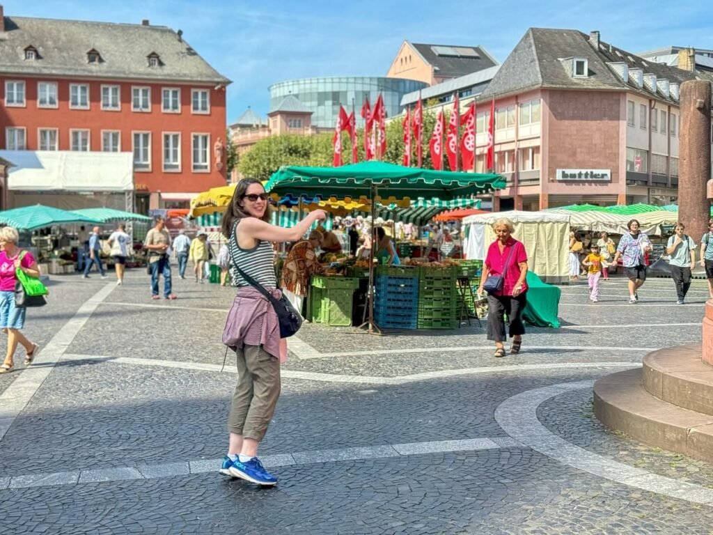 A bustling European square featuring colorful market stalls and historic buildings. Visitors enjoy a sunny day in the town center.